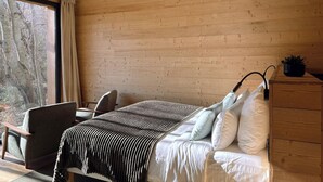Un dormitorio con techo de madera, una cama con ropa de cama blanca, una silla y un escritorio.