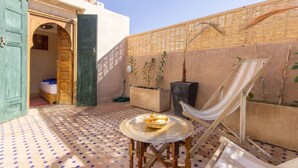 A cozy outdoor seating area with a table, chairs, and a hammock. - Riad Colette Exclusif - Médina - Petit déjeuner - Wifi (Marrakech)