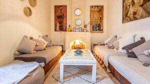 A cozy living room with a fireplace, two sofas, a coffee table, and decorative mirrors. - Riad Dar Al Barakaa - Exclusive- Breakfast (Marrakech)