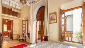 A spacious room with a large bed, a wooden desk, and a chair. There is a window with a view of the outside. - Riad Dar Al Barakaa - Exclusive- Breakfast (Marrakech)