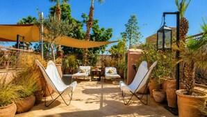 An outdoor patio with two white lounge chairs, a table, and a yellow canopy. - Riad Dar Al Barakaa - Exclusive- Breakfast (Marrakech)