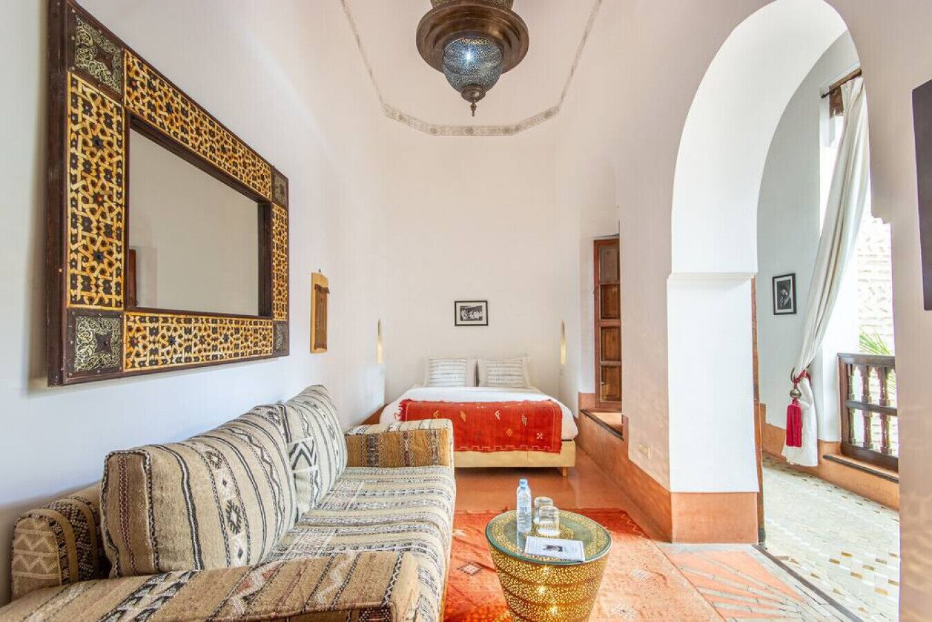 Een kamer met een bank, een bed, een kroonluchter en uitzicht op het exterieur.