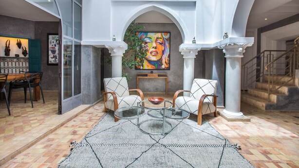 A spacious interior with a dining area, a seating area with a glass coffee table, and a staircase. - Riad Princesses des Sables-Jaccuzzi-Breakfast (Marrakesh)