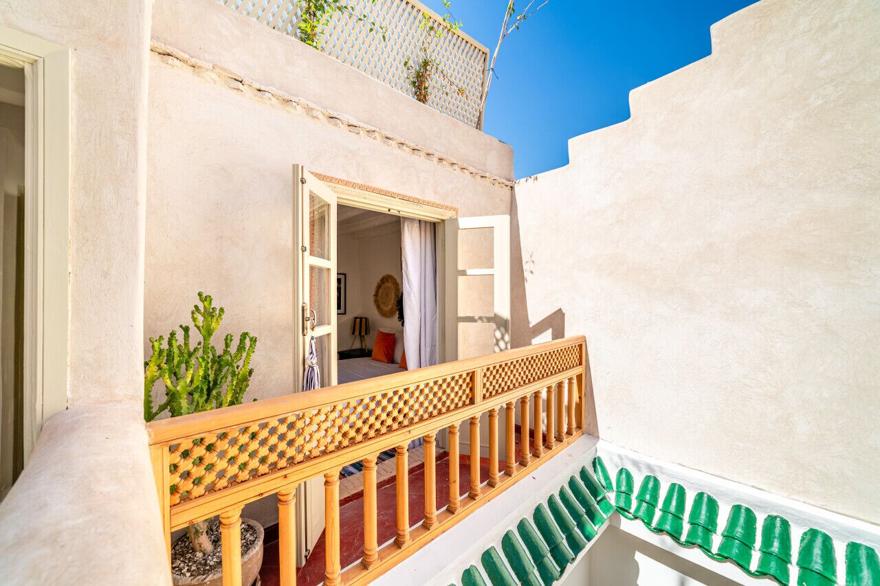 A building with a balcony, a door, and a plant.
