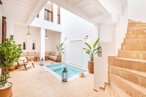 A spacious indoor pool area with a wooden staircase, seating area, and potted plants. - Riad Dar Yamina Exclusif - Morrocan Breakfast (Marrakech)