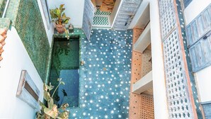 A narrow courtyard with a blue tiled floor featuring white star patterns, surrounded by white walls with blue shutters. - Riad Itri (إتري) Exclusif - Marrocan Breakfast (Marrakesh)