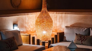Un'accogliente area relax con una lampada a sospensione in fibra intrecciata, sedute imbottite e decorazioni murali.