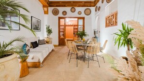 Un soggiorno accogliente con divano, tavolo da pranzo e sedie, angolo cottura con mobili in legno, e vista sul tavolo da pranzo tramite una porta aperta.
