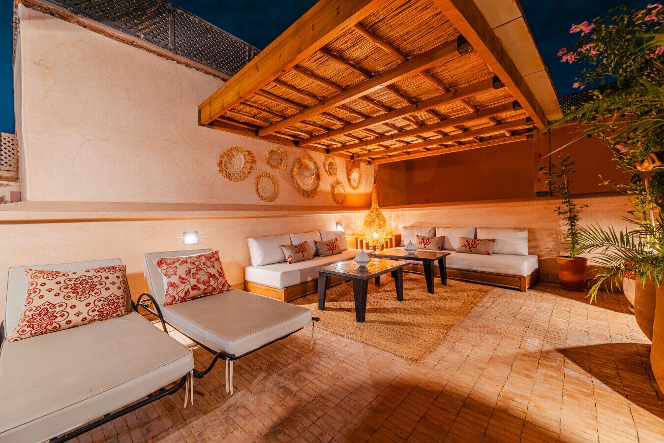 An outdoor seating area with sofas and a coffee table, a thatched roof, and decorative wall art.