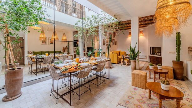 A spacious dining area with a high ceiling, large windows, and a variety of plants. - Riad Ouladi -Exclusif - 5mn Jemaa El Fnaa -Pool (Marrakesh)