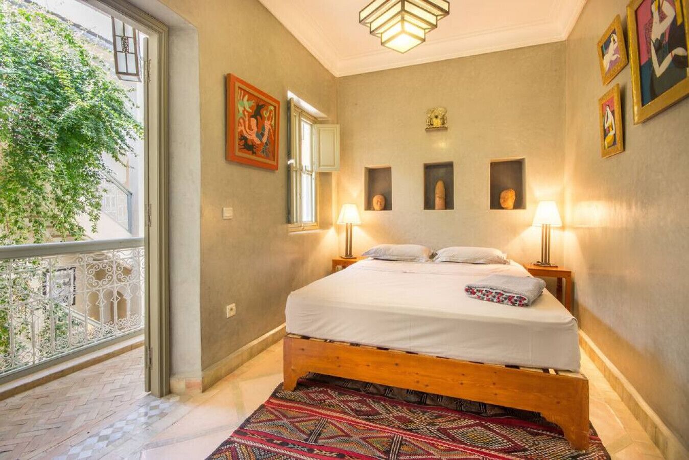 Une chambre à coucher avec un lit en bois, un tapis à motifs et des œuvres d’art accrochées aux murs.