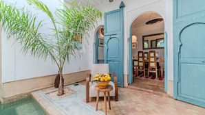 Ein Innenhof mit Pool, Essbereich mit Stühlen und Tisch sowie ein großer Baum.