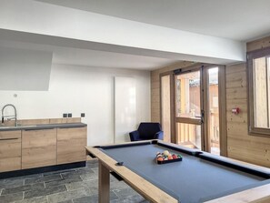 A pool table in a room with a wooden cabinet and a door leading outside. - 300m from resort center, Ground floor, view valley, fitness, sauna, balcony, parking, tv, ski locker (Montvalezan)
