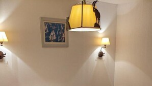 Una camera da letto con un letto in legno, una coperta rossa, due comodini, una sedia e una lampada a parete.