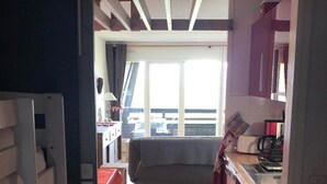 Una cocina compacta con suelo de madera, una zona de comedor con banco y vistas al exterior a través de un ventanal grande.