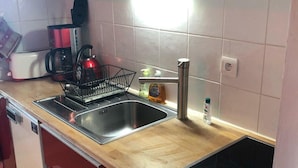 Una cocina con un lavamanos doble, cafetera, hervidor y tostadora.