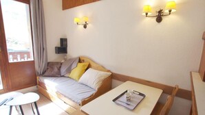 Um quarto acolhedor com uma cama de madeira, uma mesinha com bandeja e duas luminárias fixadas na parede.
