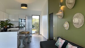 Una cocina moderna con armarios blancos, una zona de comedor con taburetes y un amplio ventanal.