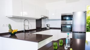 A modern kitchen with white cabinets, a stainless steel refrigerator, and a built-in oven.