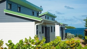 A two-story house with a green roof and a view of the sea.