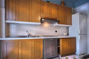A kitchen with wooden cabinets, a stainless steel dishwasher, and a white refrigerator.