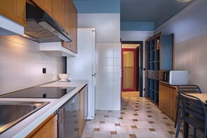 A compact kitchen with a stainless steel sink, a built-in oven, and a white refrigerator.