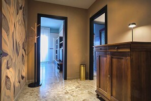 A hallway with a patterned wall, a wooden cabinet, and a floor lamp.