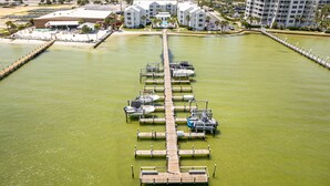 Un puerto deportivo con barcos amarrados y un muelle que conduce a un hotel con varios balcones.