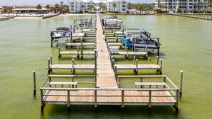 Un puerto deportivo con muelles de madera y barcos, rodeado de edificios y palmeras.