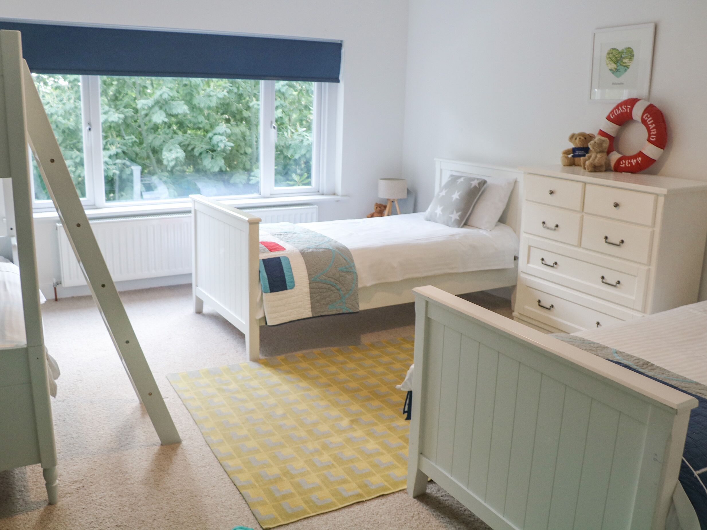A bedroom with a bed, dresser, and window with a view of greenery.