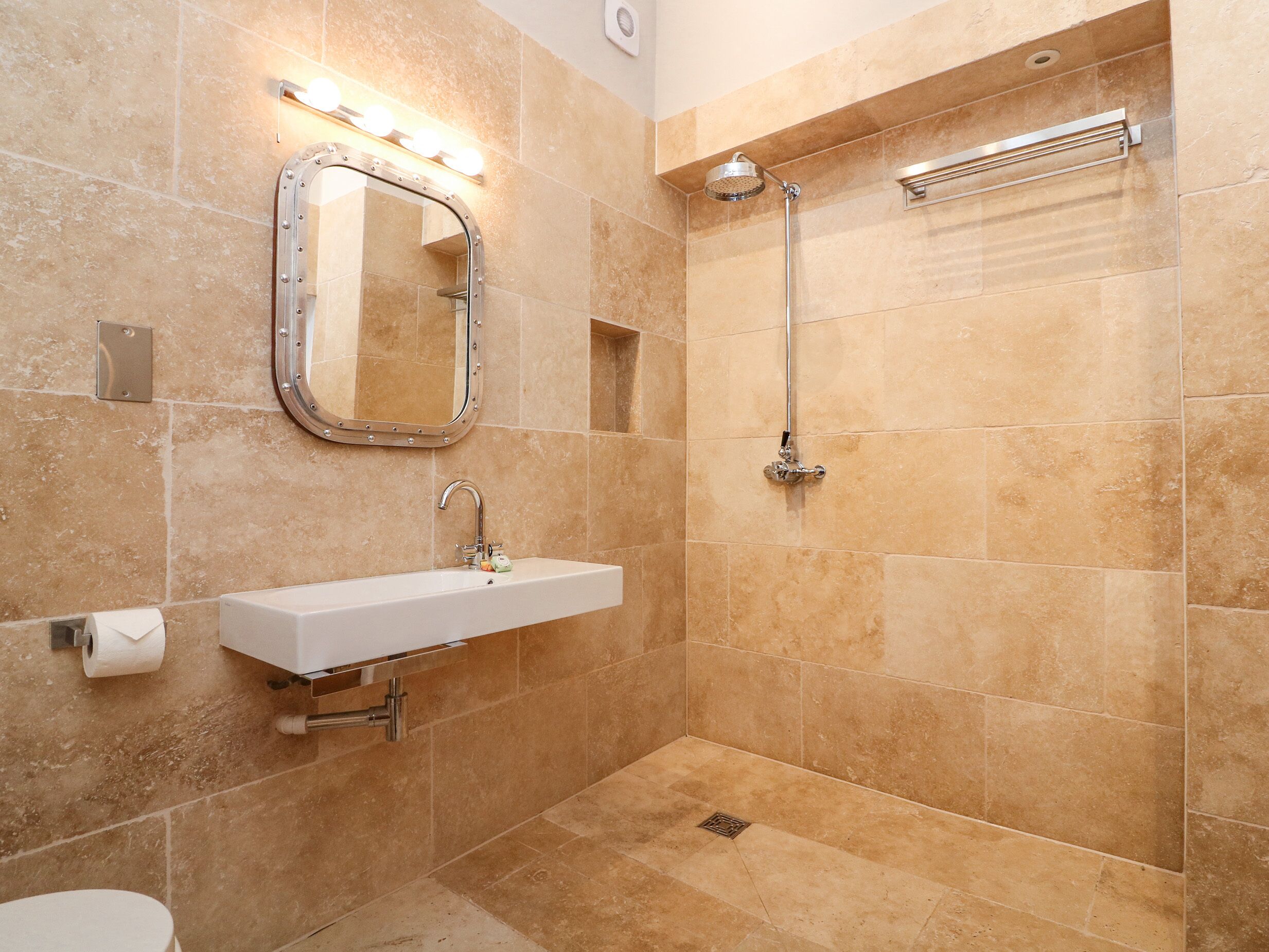 A bathroom with a sink, mirror, and shower.