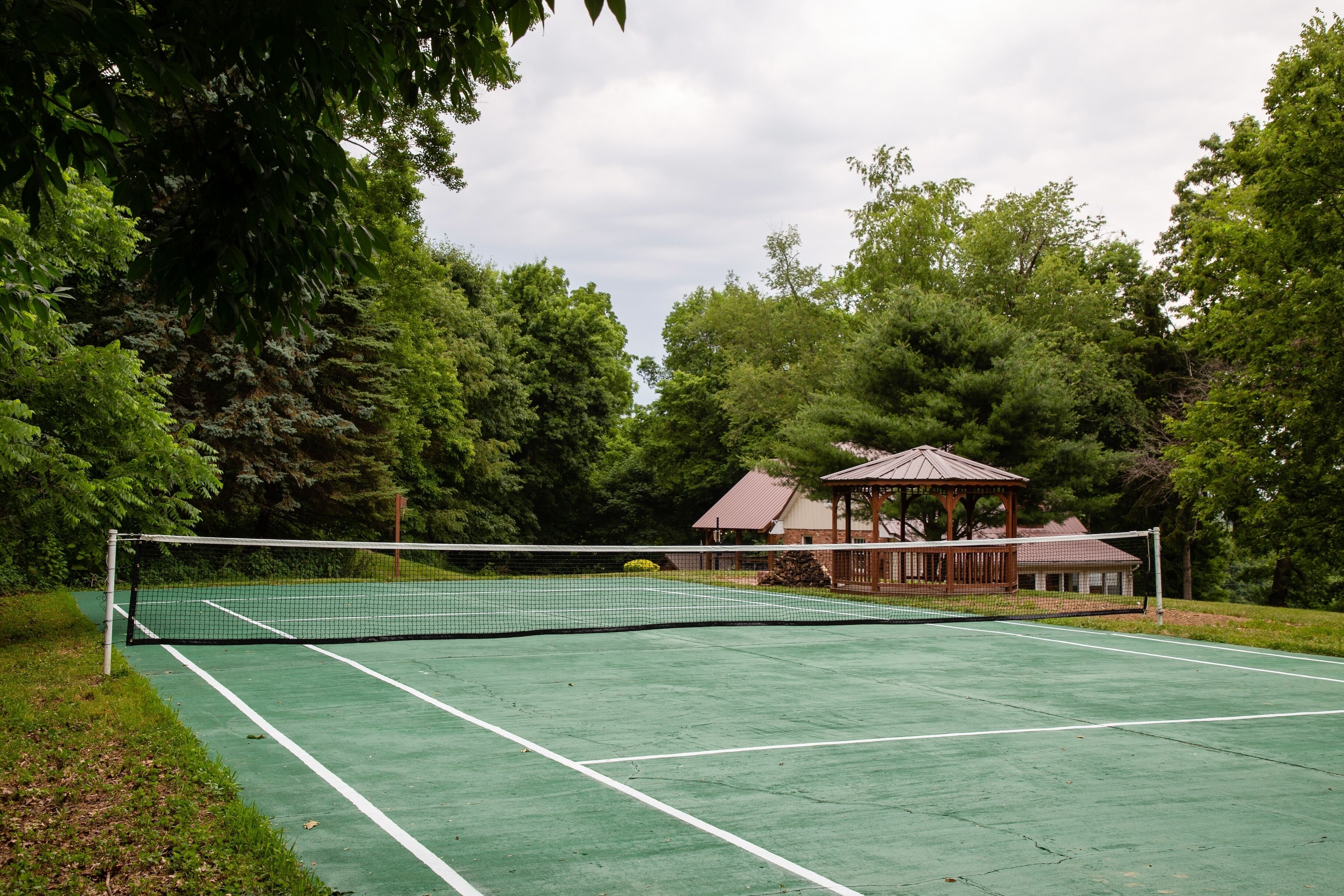 Una cancha de tenis con un pabellón al fondo.