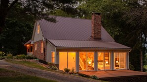 A house with a large glass door entrance, a brick chimney, and a metal roof.