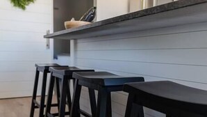 Una cocina moderna con encimera negra, armarios blancos y taburetes de madera.