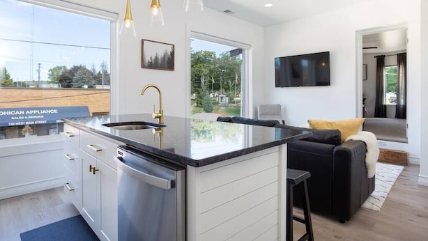 Una cocina moderna con una isla central, electrodomésticos de acero inoxidable e iluminación colgante.