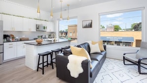 Una cocina moderna con armarios blancos, una isla central e iluminación colgante.