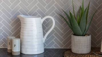 A kitchen counter with a white pitcher, two salt and pepper shakers, and a potted plant.