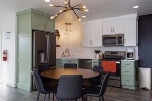A modern kitchen with a central island, stainless steel appliances, and a dining area with a round table and chairs.