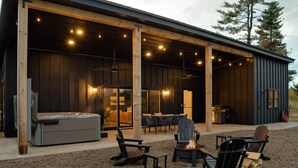 An outdoor patio area with Adirondack chairs, a fire pit, and a dining table with chairs.