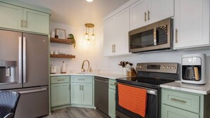 A kitchen with light green cabinets, stainless steel appliances, and a wooden countertop.