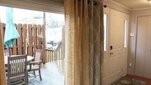 Una habitación con terraza de madera, una mesa de comedor con sillas, un tapete estampado y una puerta con ventana.