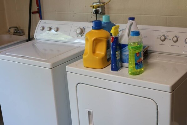 A laundry area with two washing machines and various cleaning supplies on top. - Mohican Haven Lodge. (Union Township)