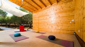 Un interior de madera con colchonetas de ejercicio y cojines de colores.