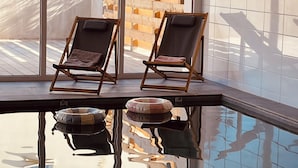 Two lounge chairs by a poolside with a tiled wall and a wooden fence in the background. - Ground floor holiday apartment for 4 people (Saint-Pierre-Quiberon)