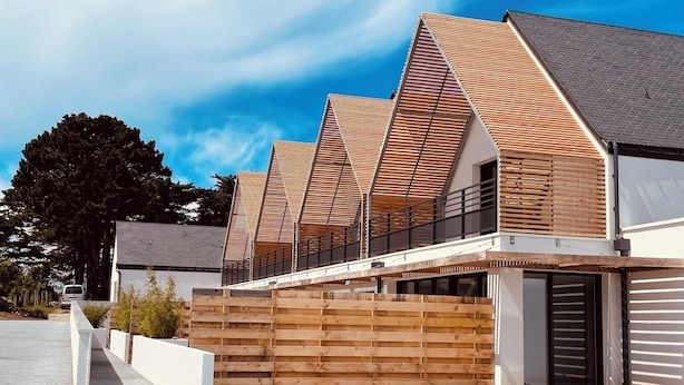 A modern two-story house with a sloped roof, wooden exterior, and a small front porch. - Ground floor holiday apartment for 4 people (Saint-Pierre-Quiberon)