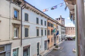 Una calle estrecha con edificios históricos, una torre del reloj y mesas al aire libre.