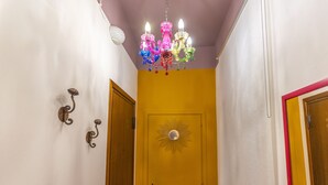 A hallway with a yellow door, a white wall, and a colorful chandelier. - -STUDIO ARENA (Verona)