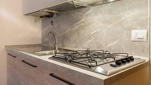 A kitchen with a gas stove, stainless steel sink, and marble backsplash. - -STUDIO ARENA (Verona)