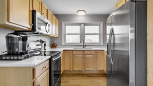 Una cocina moderna con armarios de madera, electrodomésticos de acero inoxidable y un ventanal que proporciona luz natural.