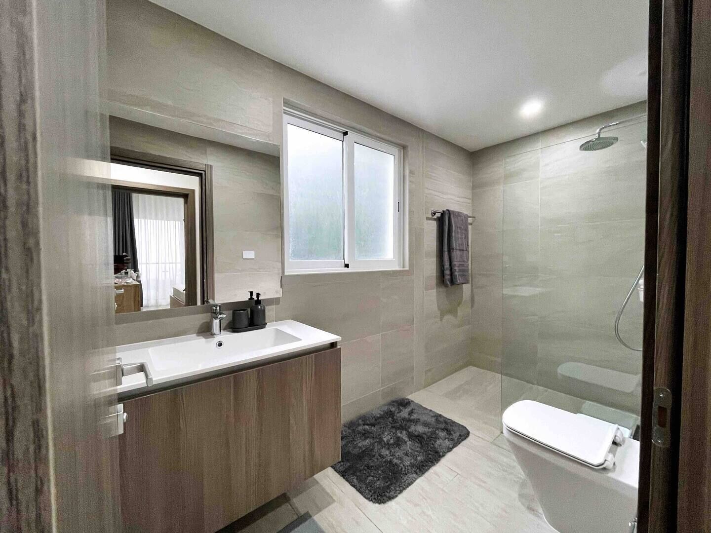 Un baño moderno con un espejo grande, un lavabo, un inodoro y una ducha.